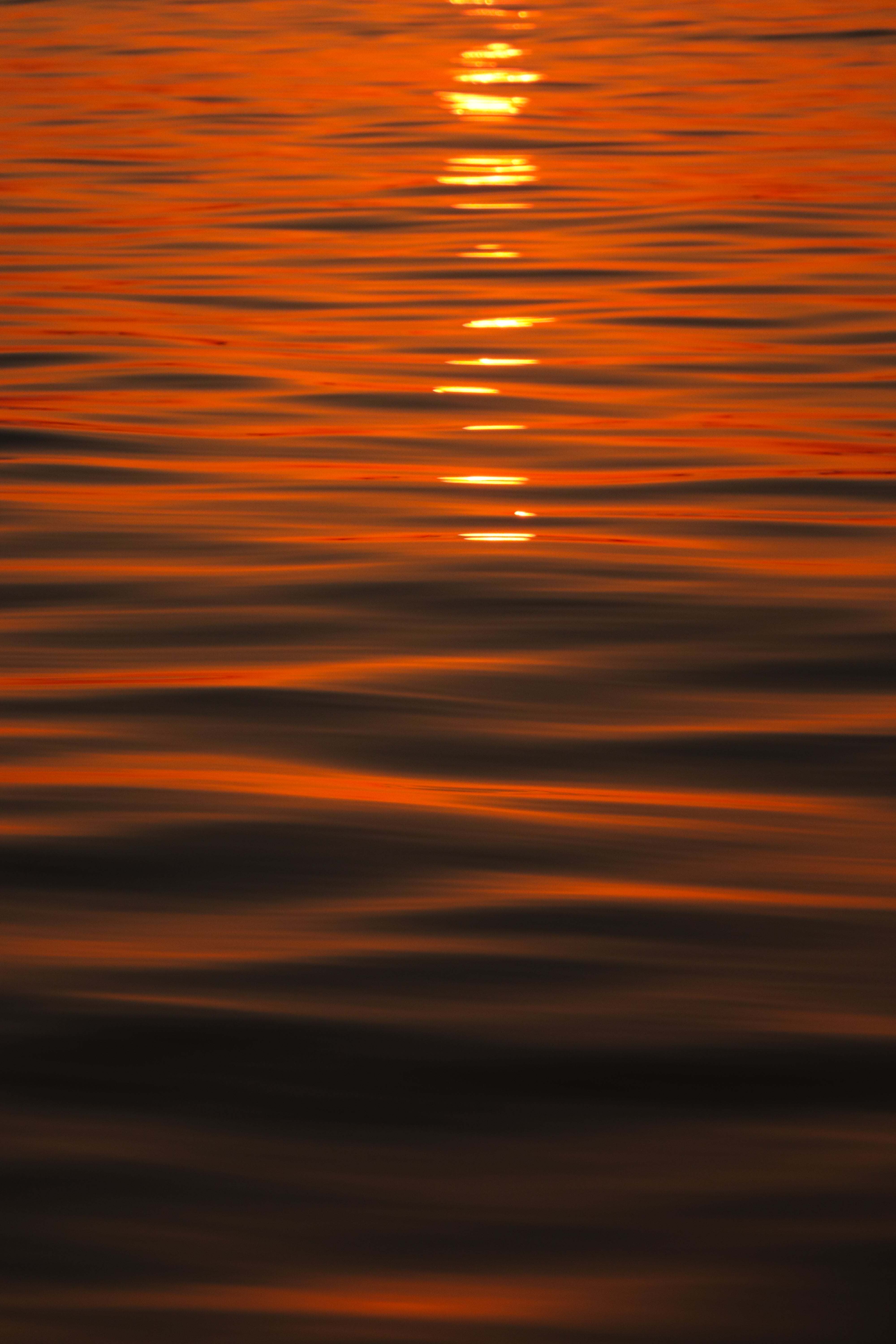Reflejos naranjas del atardecer sobre el agua